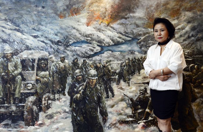 Kim Mi-jung poses next to an illustration of U.S. Marines retreating during the Battle of the Chosin Reservoir.   Park Hae-mook/The Korea Herald