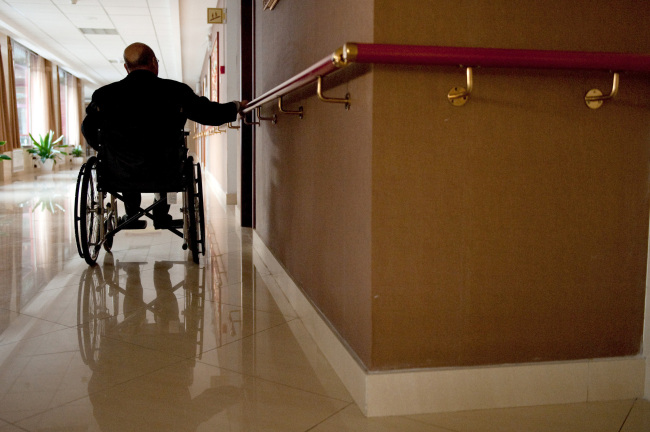 An elderly wheelchair user holds a wall-mounted bar to propel himself at the Beijing Sunshine International Care House
in Beijing. (Bloomberg)