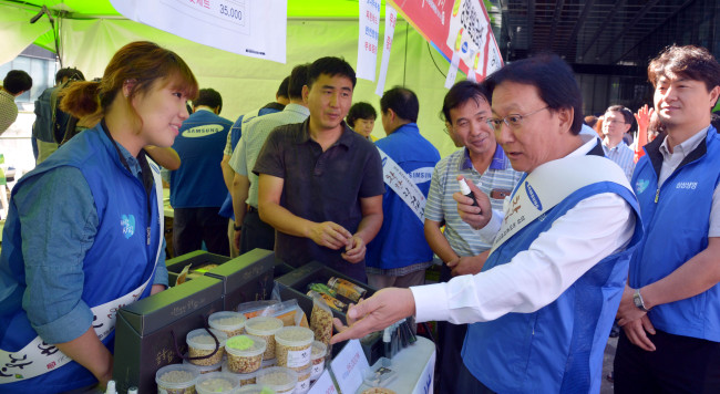 Park Keun-hee (right), vice chairman & CEO of Samsung Life Insurance, asks about agricultural products in a market at the Samsung Electronics headquarters in Seoul on Wednesday, where consumers can buy agricultural and fishery products directly from farmers and fishers. The group opened markets at 35 of its affiliates across the country.   Kim Myung-sub/The Korea Herald