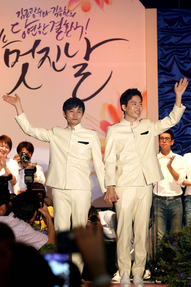 Kim Jho Kwang-soo (left) and his same-sex partner Kim Seung-hwan wave to well-wishers in the nation’s first outdoor “wedding” ceremony on a temporary stage in central Seoul on Saturday.   Yonhap News