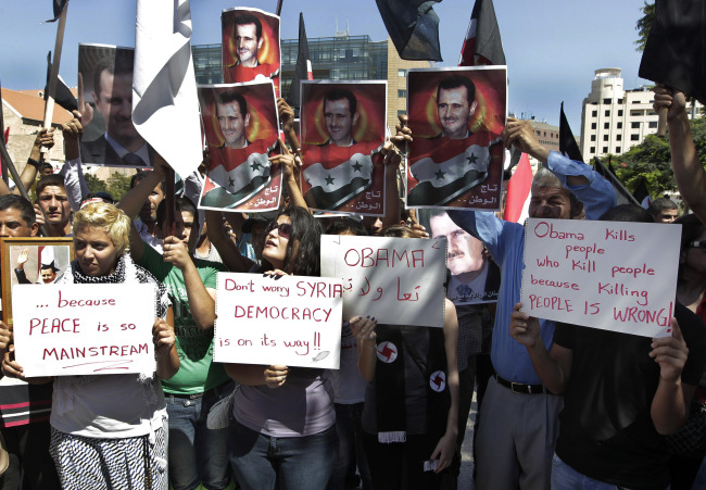 Members of the Syrian Social Nationalist Party chant slogans in front of the United Nations headquarters in Beirut on Sunday as they hold portraits of Syrian President Bashar Assad during a demonstration against a possible military strike in Syria.   AP-Yonhap News