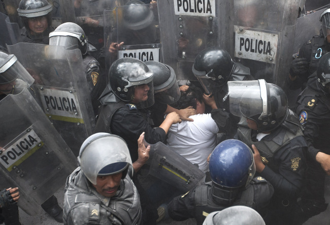 A teacher is detained by police during a clash with striking teachers who attempted to block a main avenue in Mexico City on Wednesday.   AP-Yonhap News