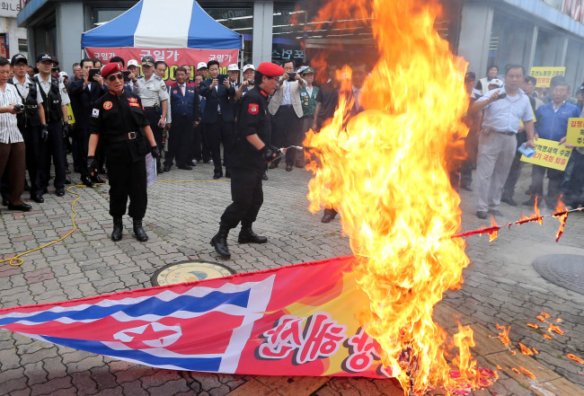 Members of a conservative non-governmental organization burn a banner carrying flags of North Korea and the Unified Progressive Party in Daejeon on Thursday.   Yonhap News
