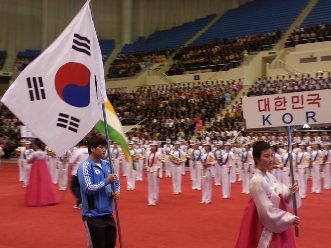 A South Korean athlete carries the country’s national flag at the opening ceremony for the 2013 Asian Cup and Interclub Weightlifting Championship in Pyongyang, North Korea, Thursday.   Yonhap News