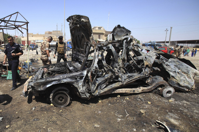 Iraqi security forces inspect the site of a car bomb attack in Basra, Iraq, Sunday.   AP-Yonhap News