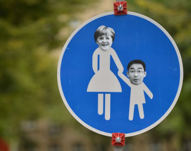The portraits of German Chancellor Angela Merkel from the Christian Democratic Union party and Philipp Roesler from her previous coalition partner, the free democratic FDP party, are stuck on a walkway sign in Berlin’s Mitte district on Monday.   AFP-Yonhap News