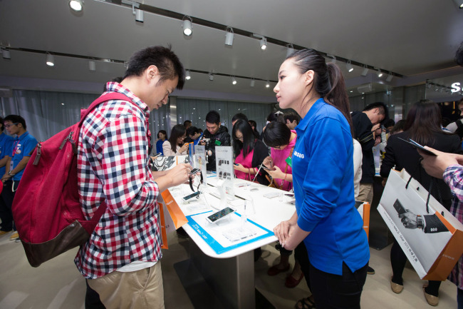 A Chinese visitor looks at Samsung’s Galaxy Note 3 and Gear at the company’s media event in Beijing on Monday.   Samsung Electronics