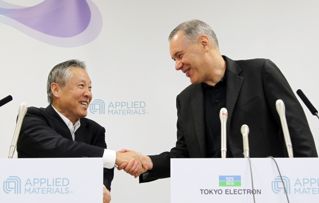Gary Dickerson (right), chief executive officer of Applied Materials Inc., shakes hands with Tetsuro Higashi, chairman of Tokyo Electron Ltd., during a news conference in Tokyo on Tuesday.    Bloomberg