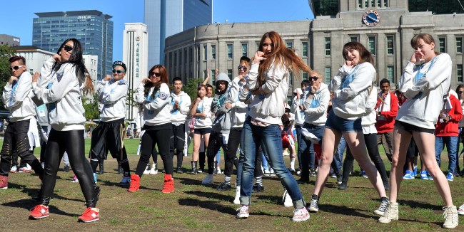The finalists of the K-Pop Festival in PyeongChang stage a flash mob performance outside Seoul City Hall on Thursday. The festival is designed to promote tourism in connection to the 2018 PyeongChang Winter Olympics.   Lee Sang-sub/The Korea Herald