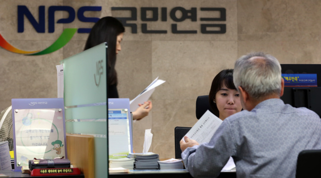 A senior consults a staff member at the National Pension Service’s Jongno branch in Seoul on Thursday after the government unveiled a scaled-down basic pension plan.   (Yonhap News)