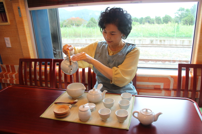 A woman shows KORAIL “S-train” riders the properties of traditional Korean tea making and drinking. (Julie Jackson/The Korea Herald)