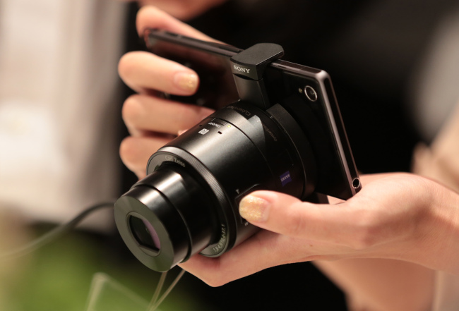 A member of the media tries out a Sony Corp. Xperia Z1 smartphone mounted with a lens-style digital camera Cyber-shot DSC-QX100 after a news conference in Tokyo on Sept. 13.   (Bloomberg)