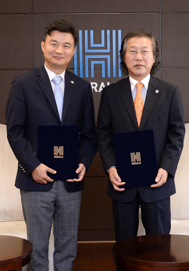 Herald Corp. CEO Lee Young-man (right) and CBNF chief Choi Jung-hwi pose after signing an agreement on Herald’s takeover of the food company at Herald Corp.’s headquarters in central Seoul last week. (Ahn Hoon/The Korea Herald)