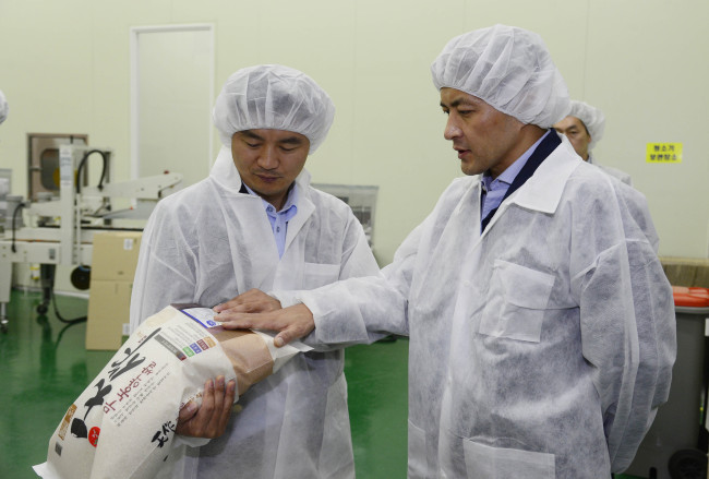 Herald Corp. chairman Hong Jung-wook (right) and Cheonbo Natural Food CEO Choi Jung-hwi inspect organic rice at the food company’s factory in Chungju, North Chungcheong Province. (Park Hae-mook/The Korea Herald)
