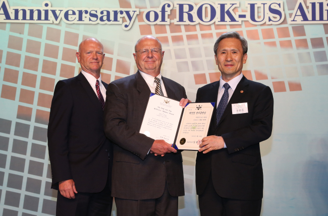 Defense Minister Kim Kwan-jin (right) confers the inaugural Paik Sun-yup ROK (Republic of Korea)-U.S. Alliance Award to late American Gen. Walton Walker, a former commander of the 8th U.S. Army, for his contribution to the alliance at a Seoul hotel on Monday. His grandson, retired Col. Walton Walker II (center), along with his son Sam Walker received the award.   (Yonhap News)
