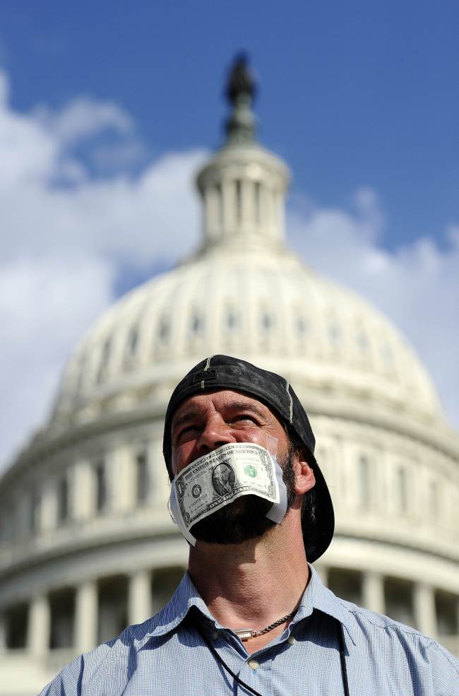A protester covers his mouth with a dollar bill as he joins others in front of the U.S. Capitol in Washington, D.C., urging congress to pass the budget bill, Tuesday.   (AFP-Yonhap News)