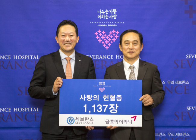 Kumho Asiana managing director Park Hong-seok (left) delivers 1,137 certificates representing blood donations to Severance Hospital general director Chung Nam-sik on Wednesday. (Kumho Asiana Group)