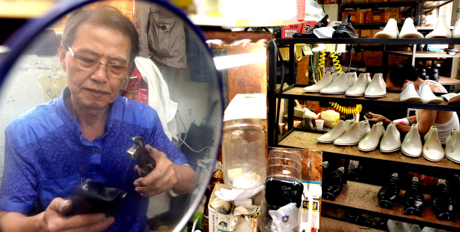 Shoemaker Kim Myung-sik, shown here reflected in a mirror, manufactures handmade shoes at a factory in Seongsu-dong, Seoul. Since Kim entered the business when he was 13, just after the Korean War, he has never stopped making shoes. Ahn Hoon/The Korea Herald