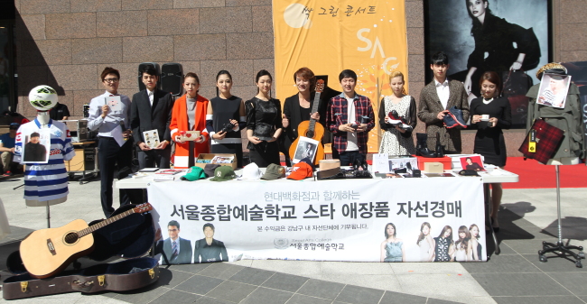 Seoul Arts College president Kim Min-sung (fourth from right) and students sell items donated by celebrities at a charity bazaar at Hyundai Department Store at COEX in Seoul on Friday.   (Seoul Arts College)