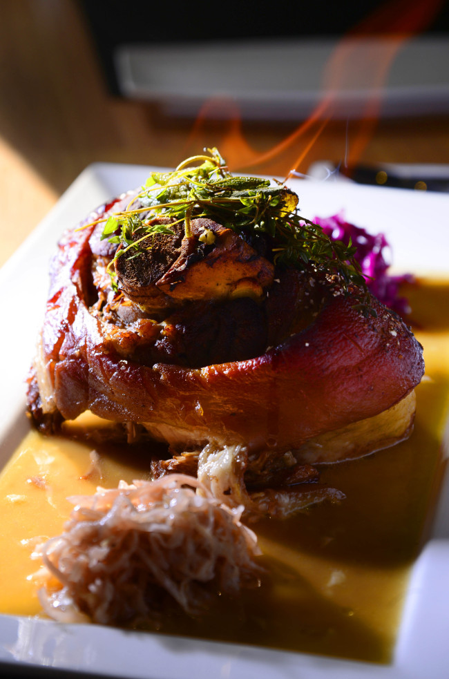 “Dark Beer Baked Pig Leg Midgard Style with Danish Red Wine Cabbage” arrives meltingly tender on the inside, crisp on the outside and crowned with a flaming sprig of rosemary. (Park Hae-mook/The Korea Herald)