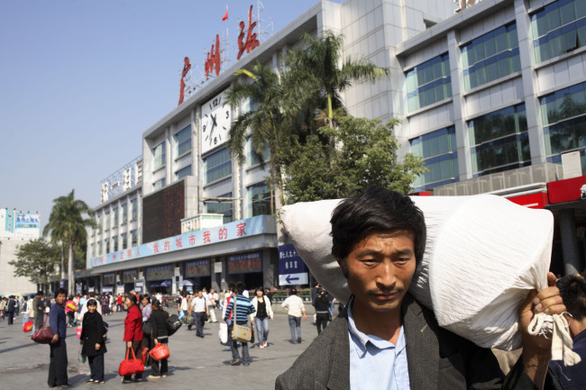 Migrant workers walk outside the main train station in Guangzhou, China.   Bloomberg