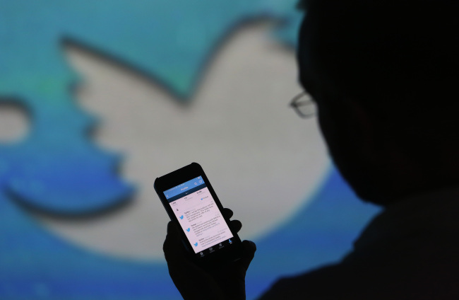 A user checks a Twitter feed on the screen of an Apple Inc. iPhone 5 in London.    Bloomberg