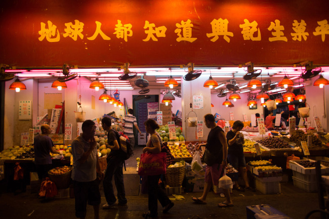 Pedestrians and shoppers walk past a fruit store in the Sham Shui Po area of Hong Kong.   Bloomberg