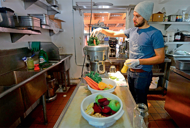 Alexander Mendez works the juicing machine at the Silver Lake Juice Bar in Los Angeles, California.   AFP