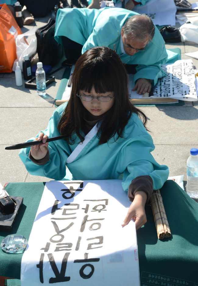A girl tries her hand at Hangeul calligraphy at a calligraphy competition marking the 567th anniversary of the promulgation of Hangeul at Gwanghwamun Square in central Seoul, Wednesday.    (Chung Hee-cho/The Korea Herald)