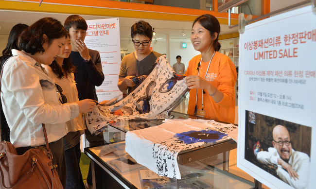 Visitors at the Herald Design Market look at a Hangeul print scarf designed by Lie Sang-bong at Blue Square in Hannam-dong, Seoul, Wednesday.   (Lee Sang-sub/The Korea Herald)