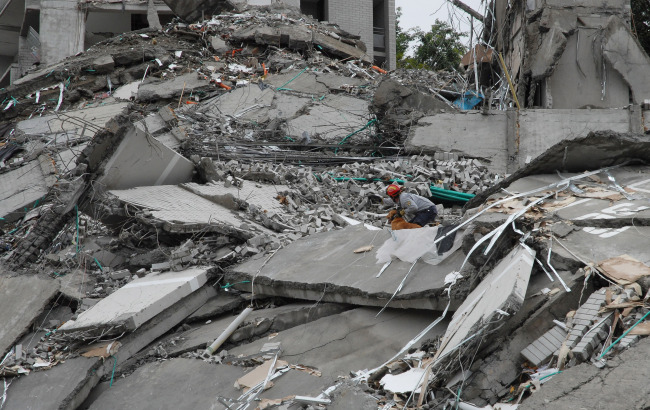 A rescue worker searches the remains of a building that collapsed Saturday, in Medellin, Colombia, Sunday.   (AP-Yonhap News)