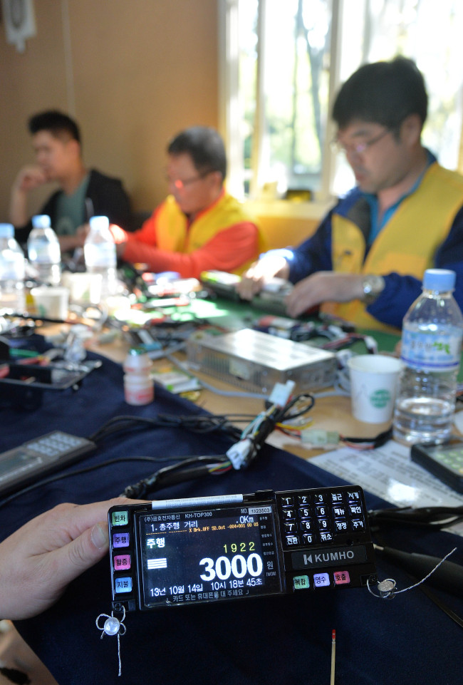 Workers reset taxi meters at a Nanjicheon Park parking lot, Seoul, Monday as a rise in basic fare in the city from 2,400 won to 3,000 won comes into force on the same day.   (Lee Sang-sub/The Korea Herald)