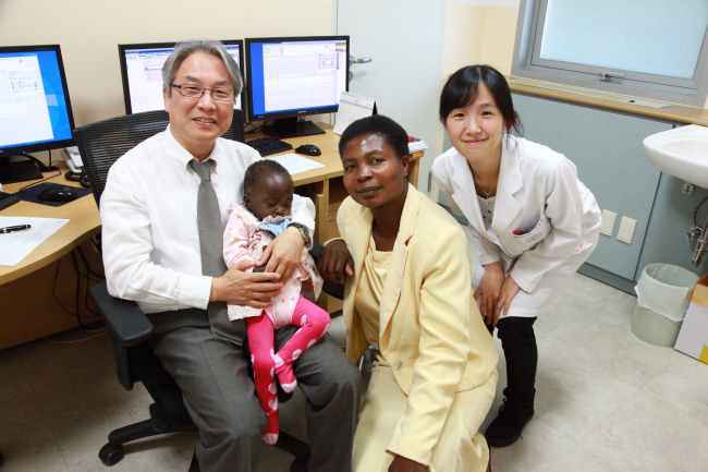Seo Dong-man (left), cardiothoracic surgeon of Konkuk University Medical Center, holding Success Kudzaishe Zingombe, poses with her mother Mariam Chikono, 36, after completing a successful surgery on the child.    Konkuk University Medical Center
