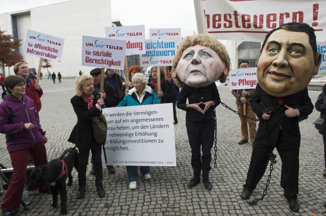 Protesters wearing masks of German Chancellor Angela Merkel and chairman of the German Social Democratic Party Sigmar Gabriel stage a rally against social injustice ahead of the third round of talks on forming a coalition government in Berlin on Monday.   (AFP-Yonhap News)