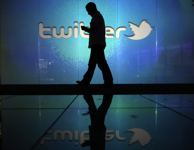A user checks his smartphone in front of a Twitter logo in London.     Bloomberg