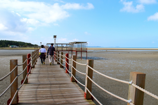 Visitors walk across the Jjangttungeo Bridge over mud flats on the southern coast of Jeungdo. Julie Jackson/The Korea Herald