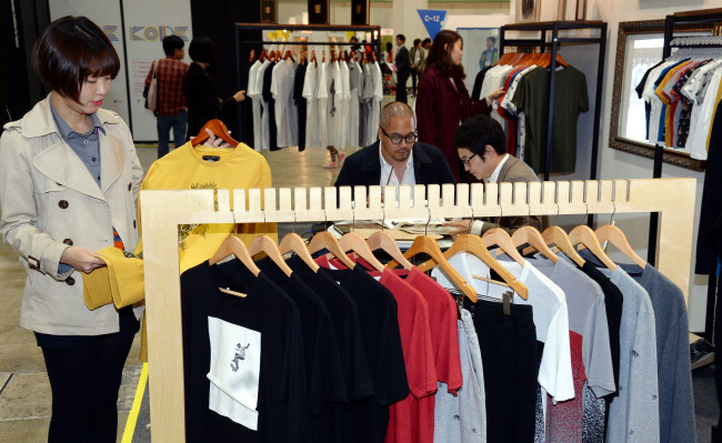 Visitors at the Fashion Kode 2013 browse items of local brand, TEE LIBRARY, at Coex in Samseong-dong, Seoul, Thursday.   Ahn Hoon/The Korea Herald