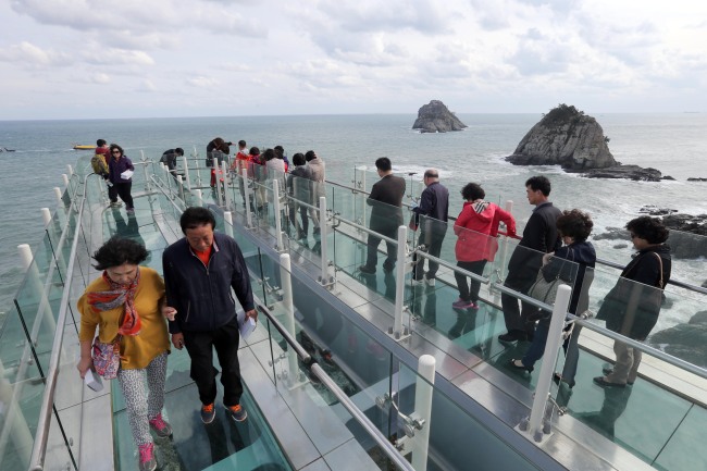 Tourists stroll on the newly opened skywalk with a view of Oryukdo Island on Friday. Yonhap News