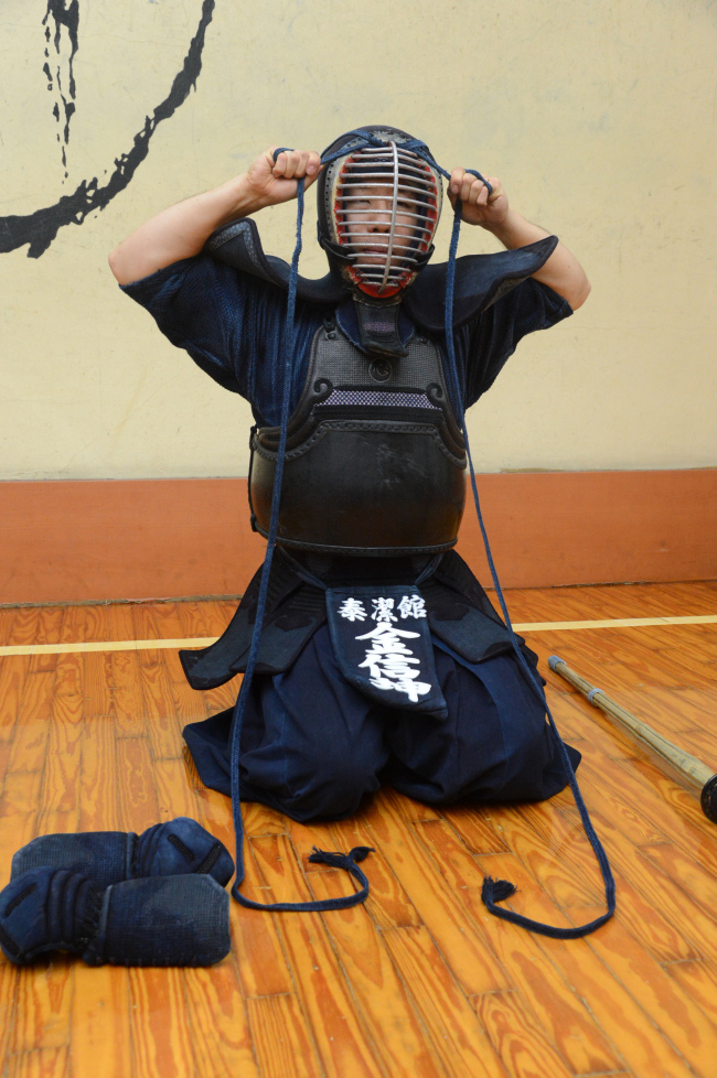 Kim Shin-gon tightens the cord of his “homyeon,” a helmet with a wire grill. Chung Hee-cho/The Korea Herald