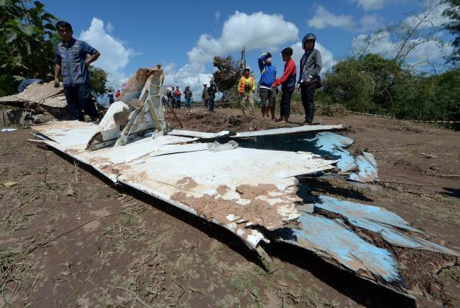 Lao villagers look at part of a wing from the Lao Airlines plane crash two days before, along the bank of the Mekong river in Pakse town on October 18, 2013.  AFP-Yonhap News