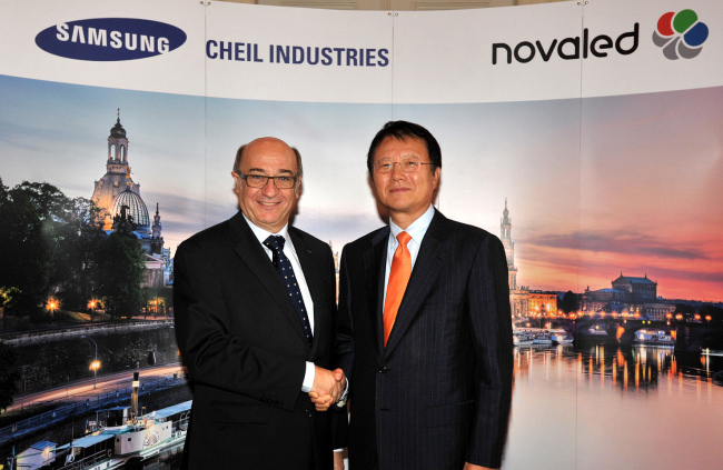 Park Jong-woo (right), CEO of electronic materials firm Cheil Industries, and Gildas Sorin, CEO of Novaled AG, an organic light-emitting diode technology provider, pose at a ceremony to launch the German company as a Samsung subsidiary in Dresden, Germany, on Friday. Some Samsung Group units including Cheil Industries acquired the German firm last month.   Cheil Industries
