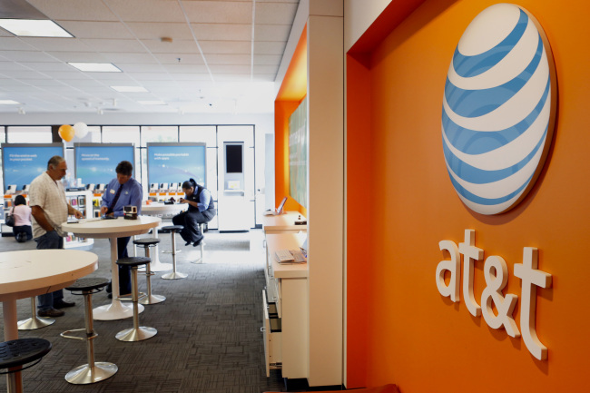An employee helps a customer at an AT&T Inc. store in Manhattan Beach, California.   Bloomberg