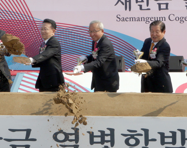 Deputy Prime Minister Hyun Oh-seok (center), along with North Jeolla Province Governor Kim Wan-joo (left) and Saemangeum Development Committee chairman Lee Yeon-taek, shovels earth during a ceremony to break the ground for the construction of a cogeneration power plant in Saemangeum on Monday.   Yonhap News