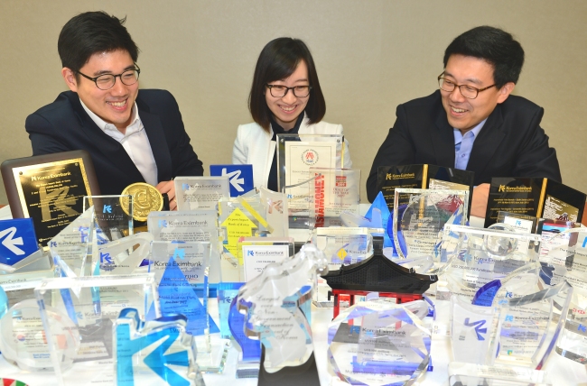 Korea Eximbank officials pose with mtn-i trophies and other global accolades awarded to the bank at its head office in Seoul on Monday.   Korea Eximbank