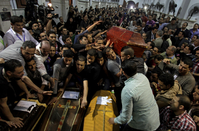 Egyptian men mourn over the coffins of four Coptic Christians who were killed late Sunday, during their funeral at Warraq’s Virgin Mary Church in Cairo on Monday.   AP-Yonhap News