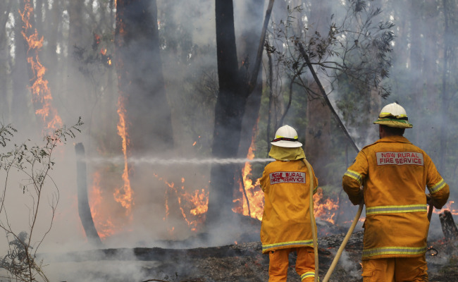 A firefighter hoses flames near houses in Bilpin, 75 kilometers west of Sydney, Australia, Tuesday.   AP-Yonhap News