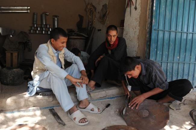 Unemployed Afghan Saber Rezayee (right) chats with his friends as he helps out at his family’s heater shop in Mazar-i-Sharif.   AFP