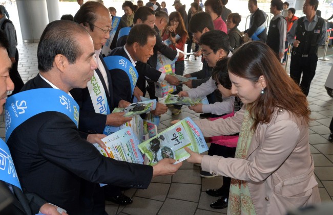 Lee Jong-koo (left), CEO of the National Federation of Fisheries Cooperatives, and officials of related groups distribute pamphlets to people in front of Seoul Station on Thursday promoting the safety of Korean fishery products.   Lee Sang-sub/The Korea Herald