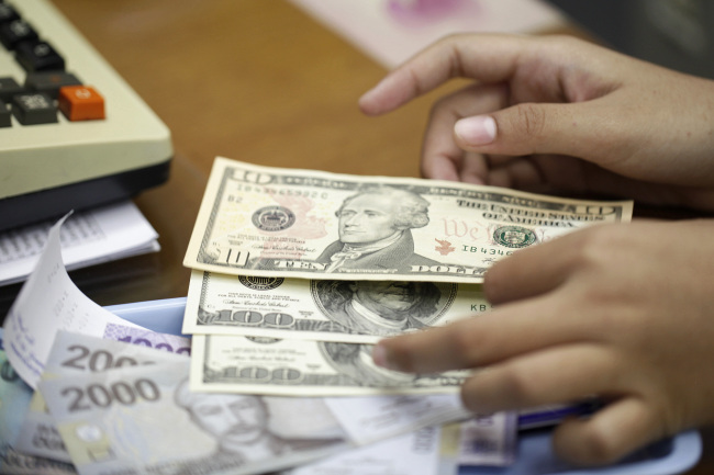 A clerk counts Indonesian rupiah and U.S. dollar banknotes at a currency exchange office in Jakarta.    Bloomberg