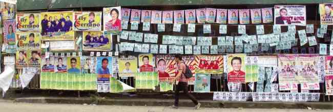 A man walks past campaign posters of candidates in Monday’s barangay elections in Quezon City.   Philippine Daily Inquirer
